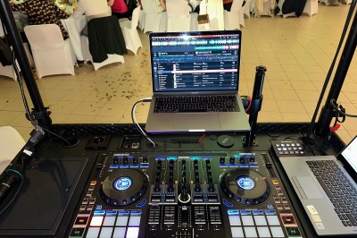 Borne de karaoké avec écran tactile affichant une interface de sélection de chansons, dans une salle animée.