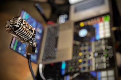 Borne de karaoké avec écran tactile affichant une interface de sélection de chansons, dans une salle animée.