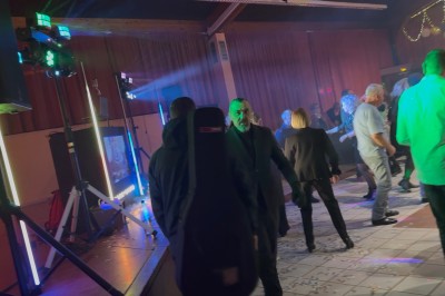 Borne de karaoké avec écran tactile affichant une interface de sélection de chansons, dans une salle animée.