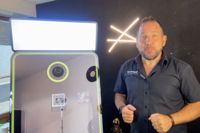 Borne de karaoké avec écran tactile affichant une interface de sélection de chansons, dans une salle animée.