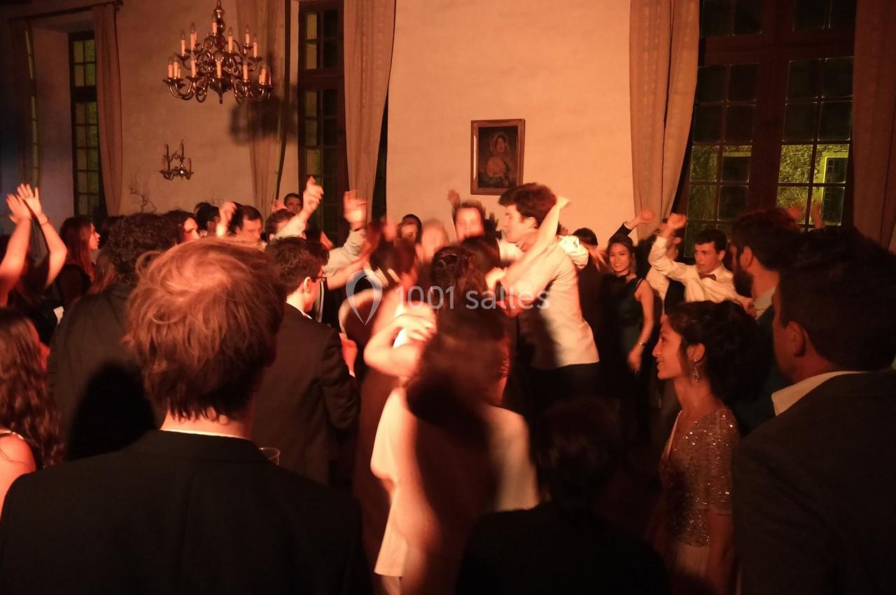 Groupe de personnes dansant dans une salle éclairée avec des lustres et de grandes fenêtres.
