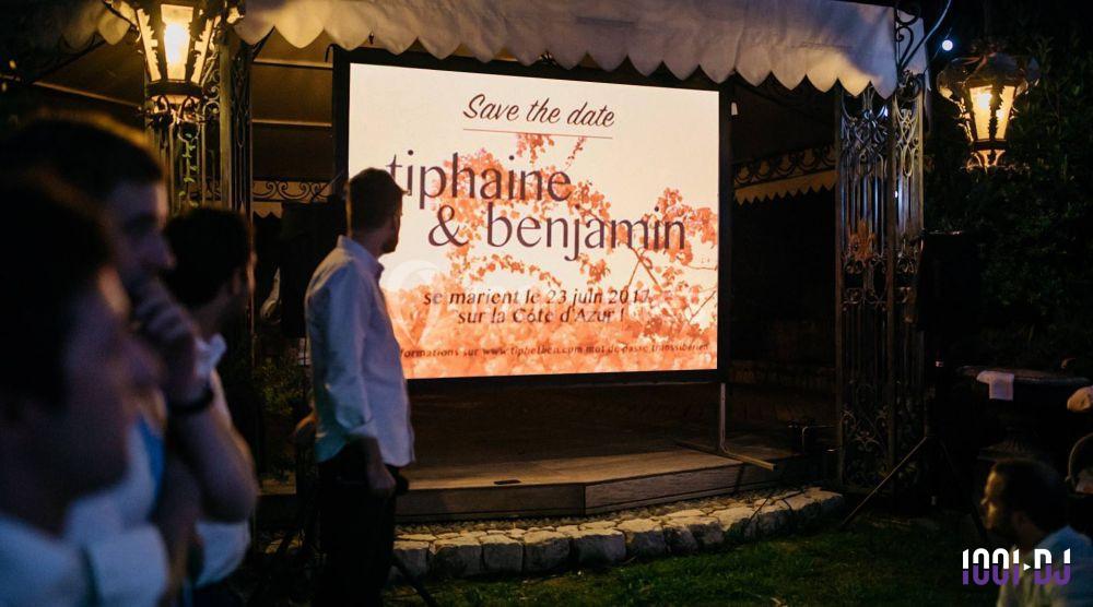 Écran affichant une invitation de mariage avec les prénoms ’Tiphaine et Benjamin’ et la date sur fond floral.