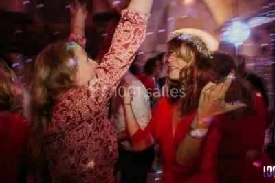 Un couple danse sur une piste éclairée par des lumières colorées, entouré de spectateurs dans une salle festive.