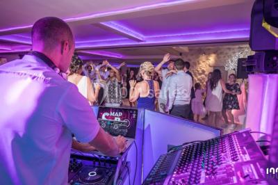 Deux hommes sur scène, l'un chante au micro tandis que l'autre pointe du doigt près d'un équipement audio.