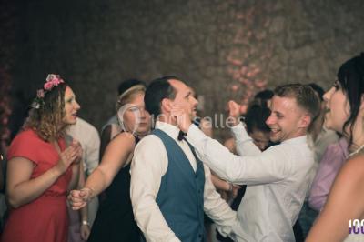 Deux hommes sur scène, l'un chante au micro tandis que l'autre pointe du doigt près d'un équipement audio.