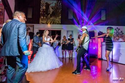 Deux hommes sur scène, l'un chante au micro tandis que l'autre pointe du doigt près d'un équipement audio.