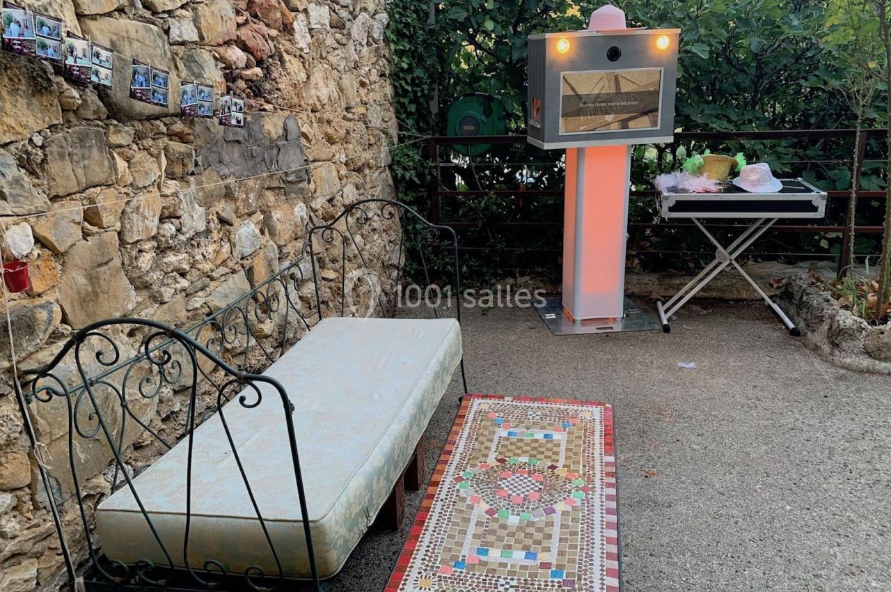 Canapé en fer forgé, table basse ornée de mosaïques et four à pizza dans une cour extérieure en pierre.