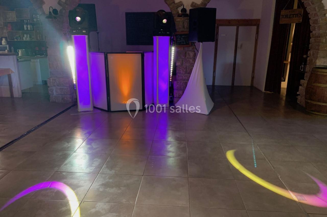 Équipement de sonorisation et éclairage coloré installé dans une salle avec sol carrelé et murs en pierre.