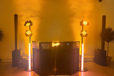 Salle décorée pour un événement avec éclairage violet, machines à fumée et équipements audio devant une baie vitrée.