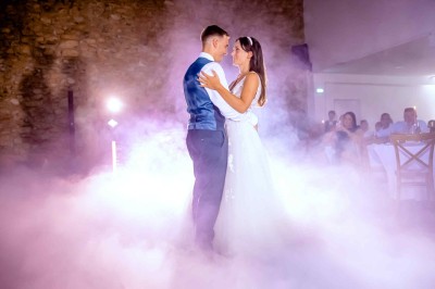 Salle décorée pour un événement avec éclairage violet, machines à fumée et équipements audio devant une baie vitrée.