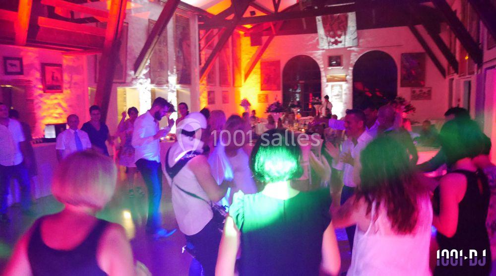 Des personnes dansent dans une salle éclairée par des lumières colorées lors d'un événement festif.