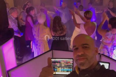 Deux hommes sur scène, l'un chante au micro tandis que l'autre pointe du doigt près d'un équipement audio.