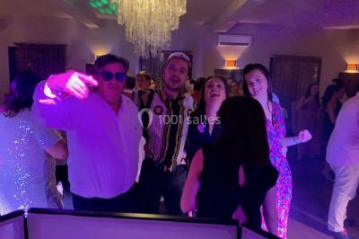 Deux hommes sur scène, l'un chante au micro tandis que l'autre pointe du doigt près d'un équipement audio.