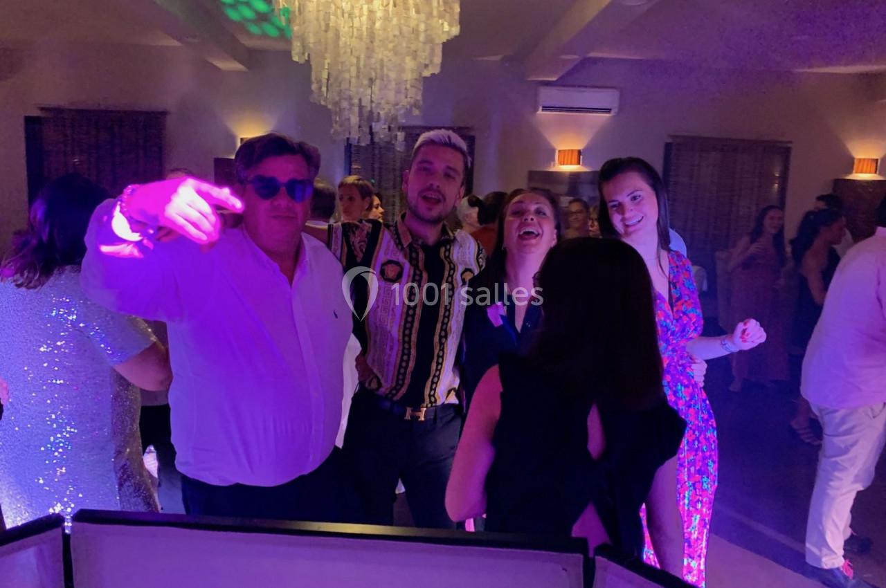 Groupe de personnes dansant et posant joyeusement sous des lumières colorées lors d'une soirée festive.