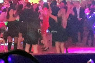 Scène de concert avec batterie, guitares, claviers et micros sous un éclairage coloré.