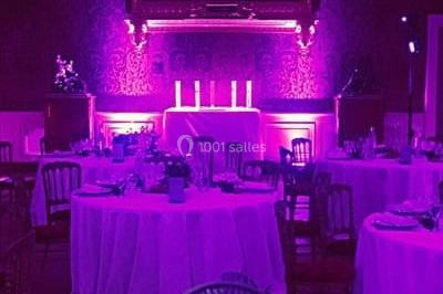 Scène de concert avec batterie, guitares, claviers et micros sous un éclairage coloré.