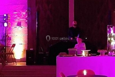 Scène de concert avec batterie, guitares, claviers et micros sous un éclairage coloré.