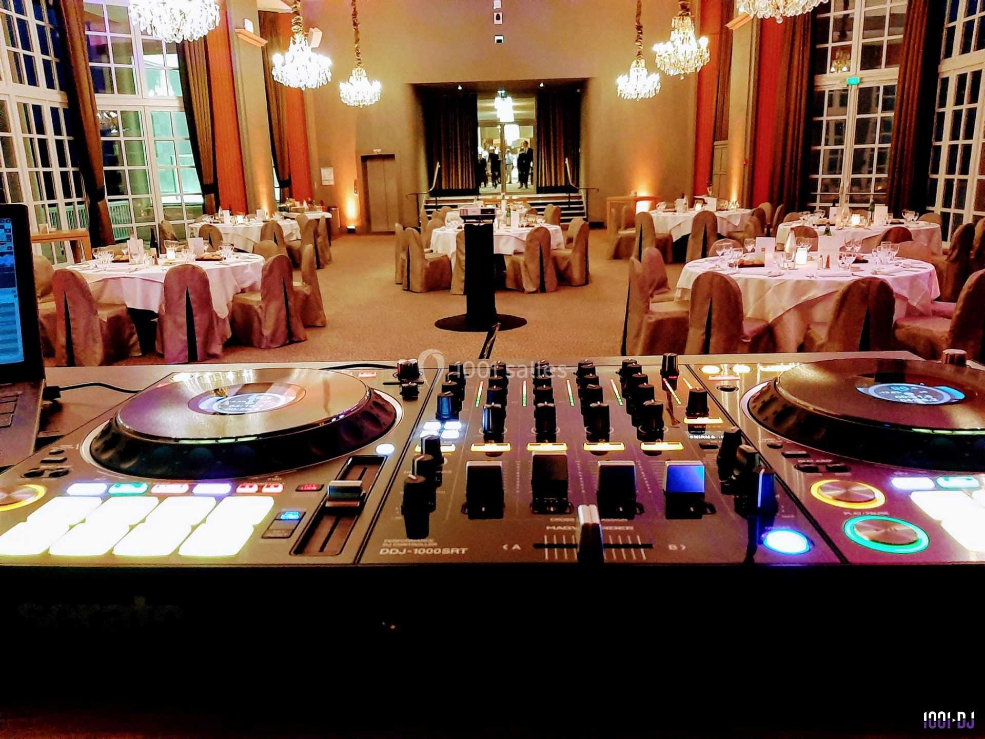 Console de DJ allumée au premier plan, avec une salle de réception élégamment décorée en arrière-plan.