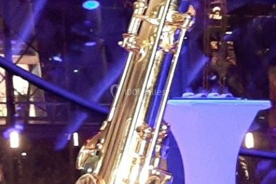 Scène de concert avec batterie, guitares, claviers et micros sous un éclairage coloré.