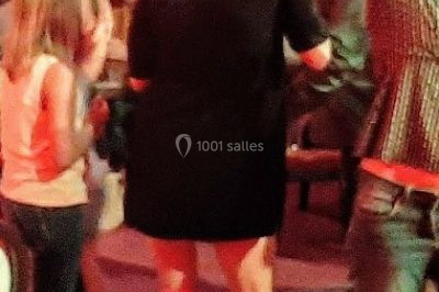 Scène de concert avec batterie, guitares, claviers et micros sous un éclairage coloré.