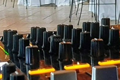 Scène de concert avec batterie, guitares, claviers et micros sous un éclairage coloré.