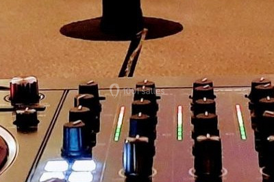 Scène de concert avec batterie, guitares, claviers et micros sous un éclairage coloré.