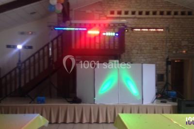 Salle décorée avec des tables dressées, des ballons et une scène équipée d'instruments de musique et de projecteurs.