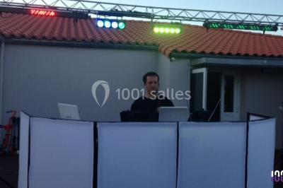 Salle décorée avec des tables dressées, des ballons et une scène équipée d'instruments de musique et de projecteurs.