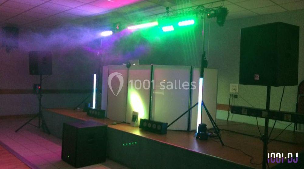 Installation de matériel de sonorisation et d'éclairage sur une scène dans une salle intérieure.