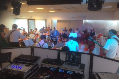 Salle décorée avec des tables dressées, des ballons et une scène équipée d'instruments de musique et de projecteurs.