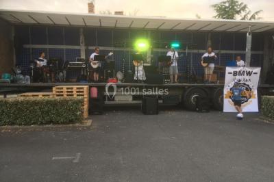 Salle décorée avec des tables dressées, des ballons et une scène équipée d'instruments de musique et de projecteurs.