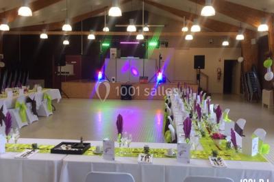 Salle décorée avec des tables dressées, des ballons et une scène équipée d'instruments de musique et de projecteurs.