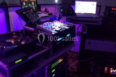 Salle décorée avec des tables dressées, des ballons et une scène équipée d'instruments de musique et de projecteurs.