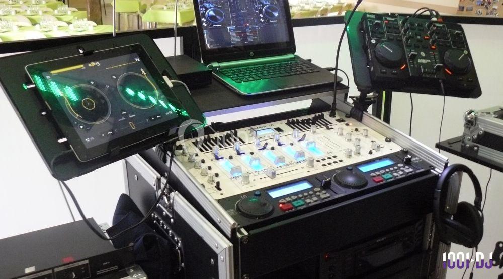 Équipement de DJ comprenant une table de mixage, deux tablettes, un ordinateur portable et des contrôleurs audio.