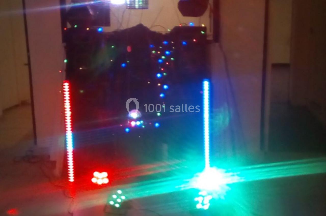 Installation de matériel de sonorisation et éclairage coloré dans une pièce, avec faisceaux lumineux rouges et verts.