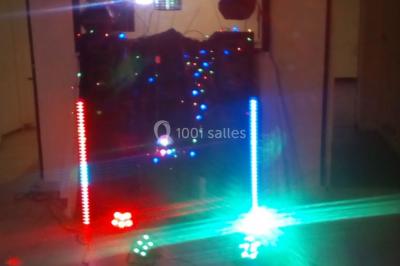 Installation de matériel de sonorisation et d'éclairage coloré sur une scène intérieure, avec des enfants au premier plan.