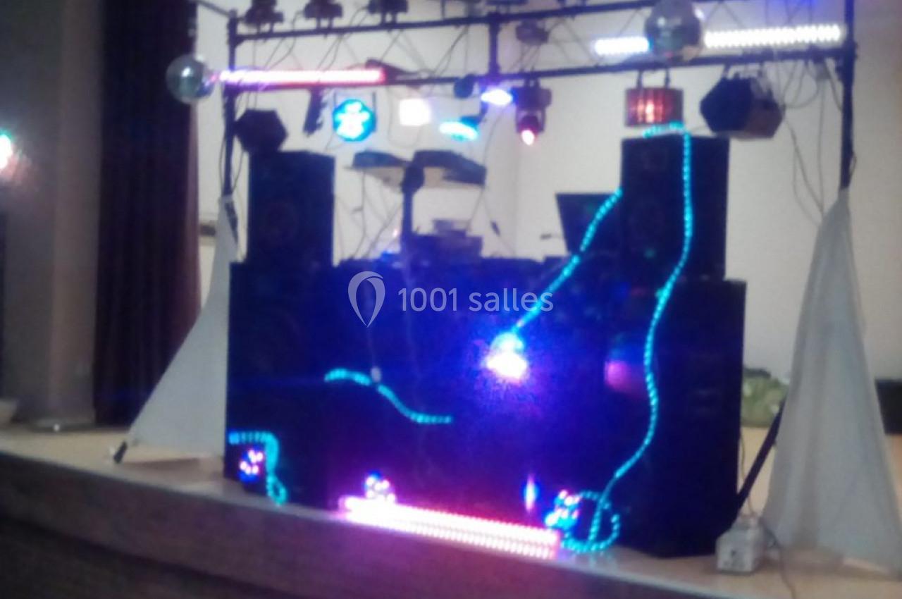 Installation de matériel de sonorisation et éclairage coloré sur une scène dans une salle intérieure.