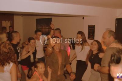 Un DJ mixant de la musique sur une table de mixage éclairée par des lumières colorées dans une ambiance nocturne.