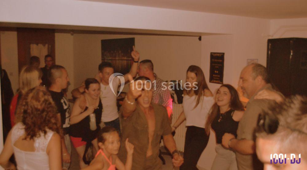 Des personnes dansent et s'amusent dans une salle intérieure éclairée, créant une ambiance festive et conviviale.