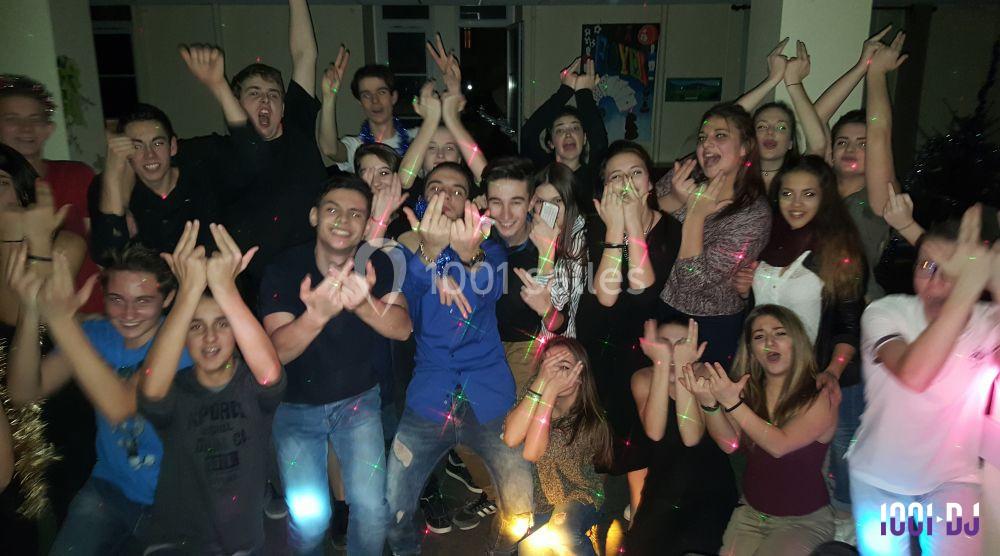 Un groupe de jeunes souriants dans une ambiance festive avec des lumières colorées en intérieur.