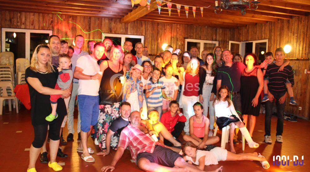 Un grand groupe de personnes pose dans une salle en bois décorée, éclairée par des lumières colorées.