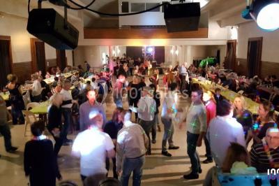 Un DJ mixant de la musique sur une table de mixage éclairée par des lumières colorées dans une ambiance nocturne.