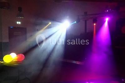 Un DJ mixant de la musique sur une table de mixage éclairée par des lumières colorées dans une ambiance nocturne.