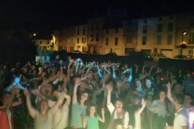 Un DJ mixant de la musique sur une table de mixage éclairée par des lumières colorées dans une ambiance nocturne.