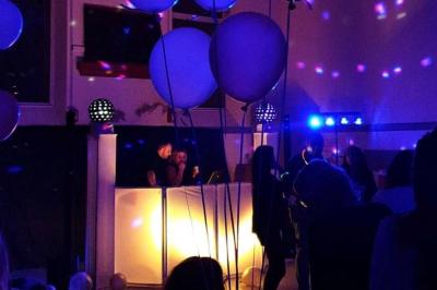 Un DJ mixant de la musique sur une table de mixage éclairée par des lumières colorées dans une ambiance nocturne.