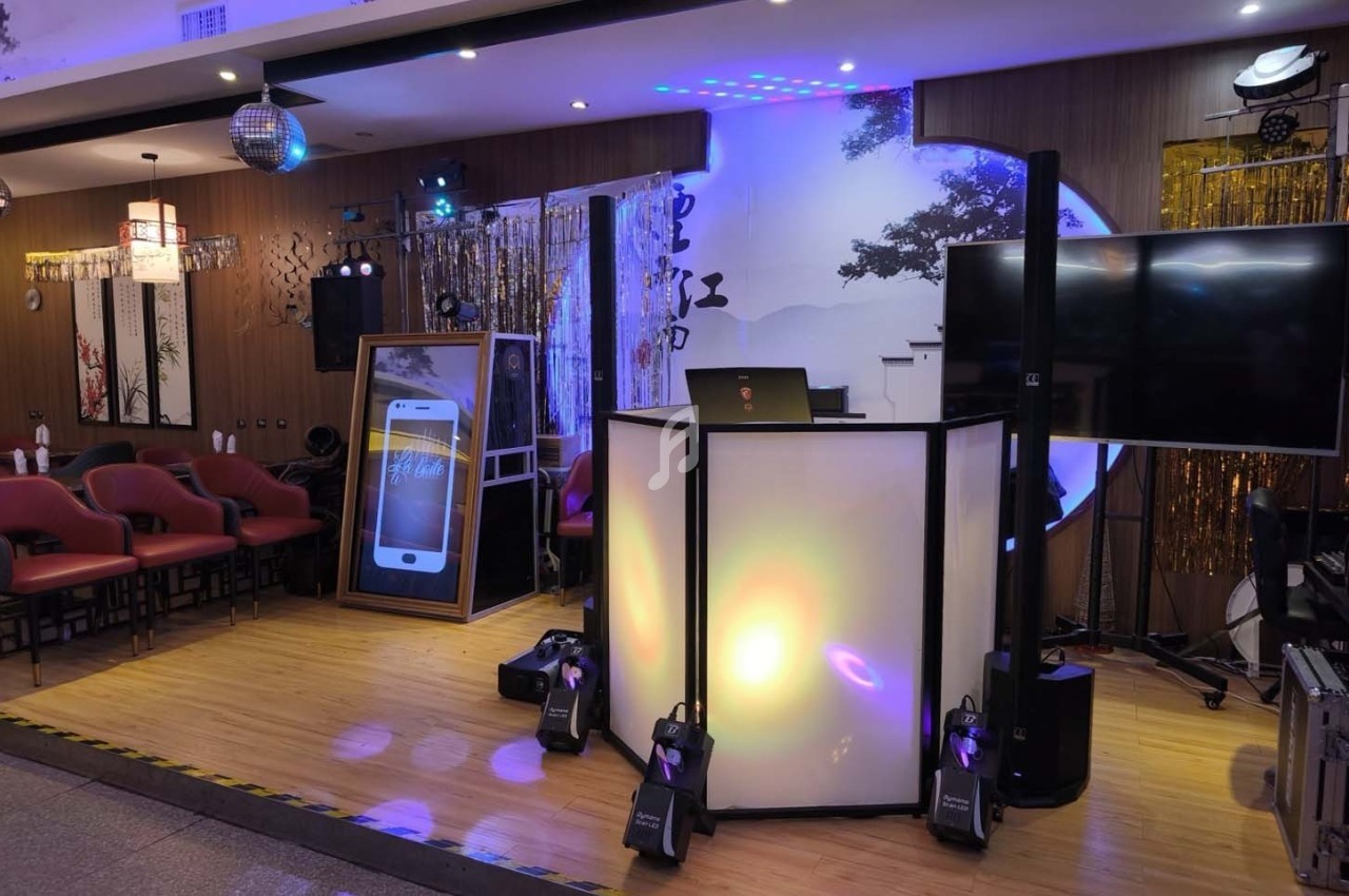 Scène intérieure avec un espace de karaoké, comprenant un pupitre éclairé, des sièges et des équipements audiovisuels.