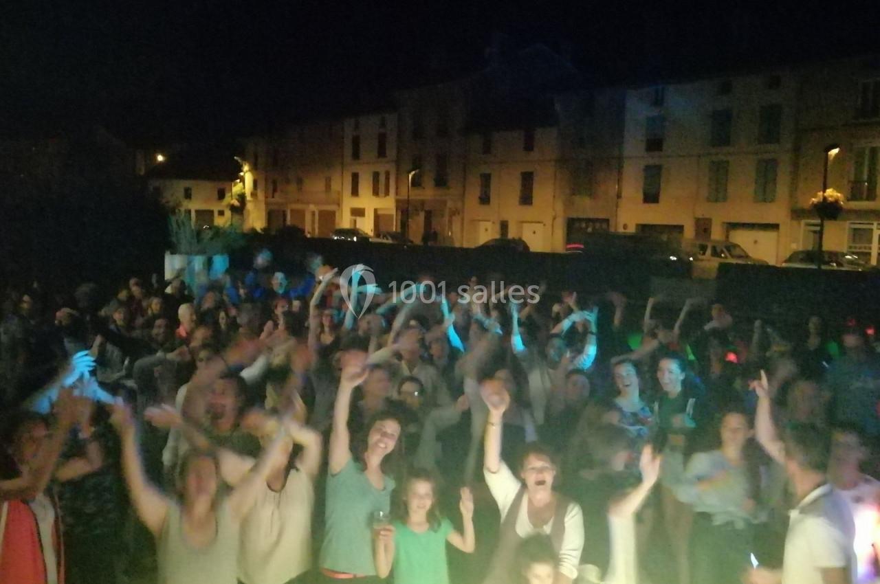 Groupe de personnes rassemblées en plein air la nuit, levant les bras dans une ambiance festive.