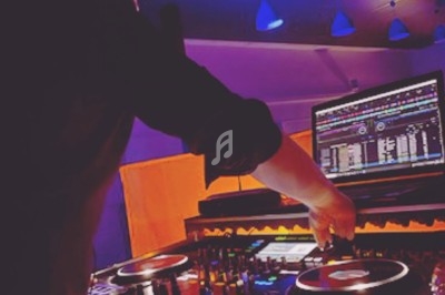 Miniature DJ Torcieu (Ain) - Monstro Event #24 Un DJ mixant de la musique sur une table de mixage éclairée par des lumières colorées dans une ambiance nocturne.