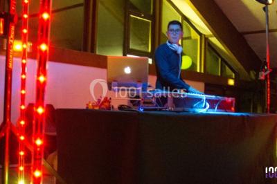 Salle de réception en plein air sous une verrière, avec tables décorées, nappes blanches et éclairage chaleureux.