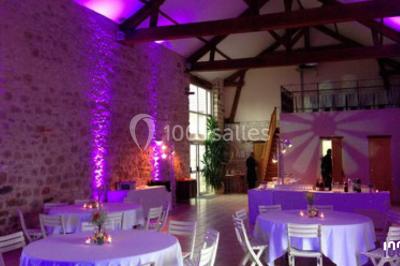 Salle de réception en plein air sous une verrière, avec tables décorées, nappes blanches et éclairage chaleureux.